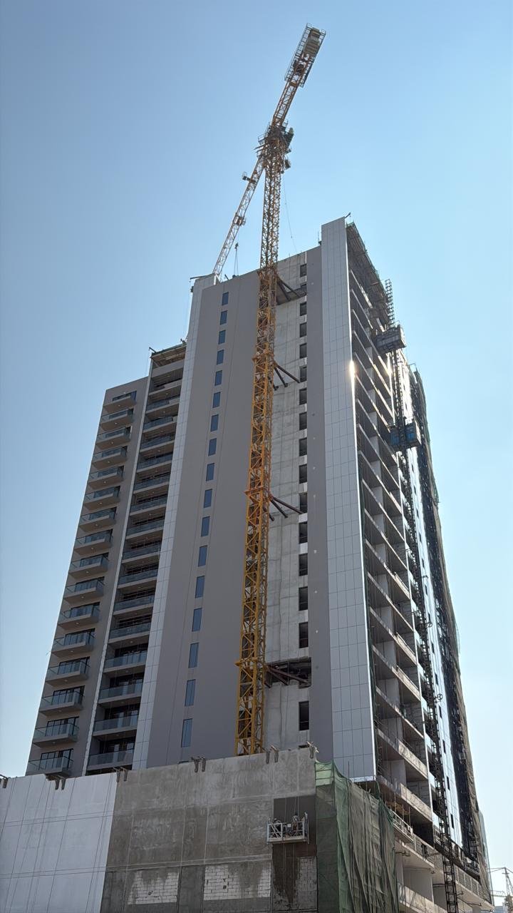 Technician working at the upper section of a tower crane with panoramic Dubai skyline view.