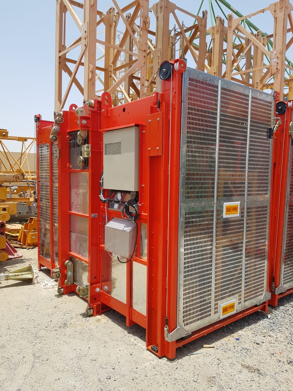 Vertical hoist rail extending to upper levels on a tower construction site.
